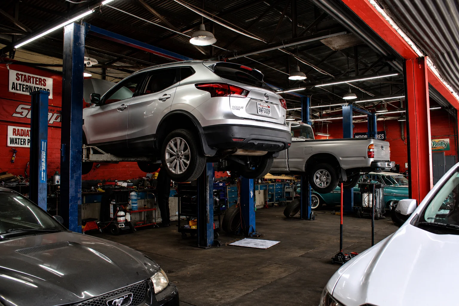 Cars and trucks being serviced on lifts inside the shop
