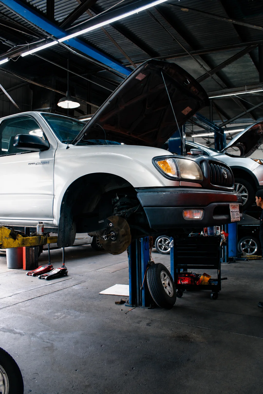 Toyota pickup on a lift with its front wheel removed for service